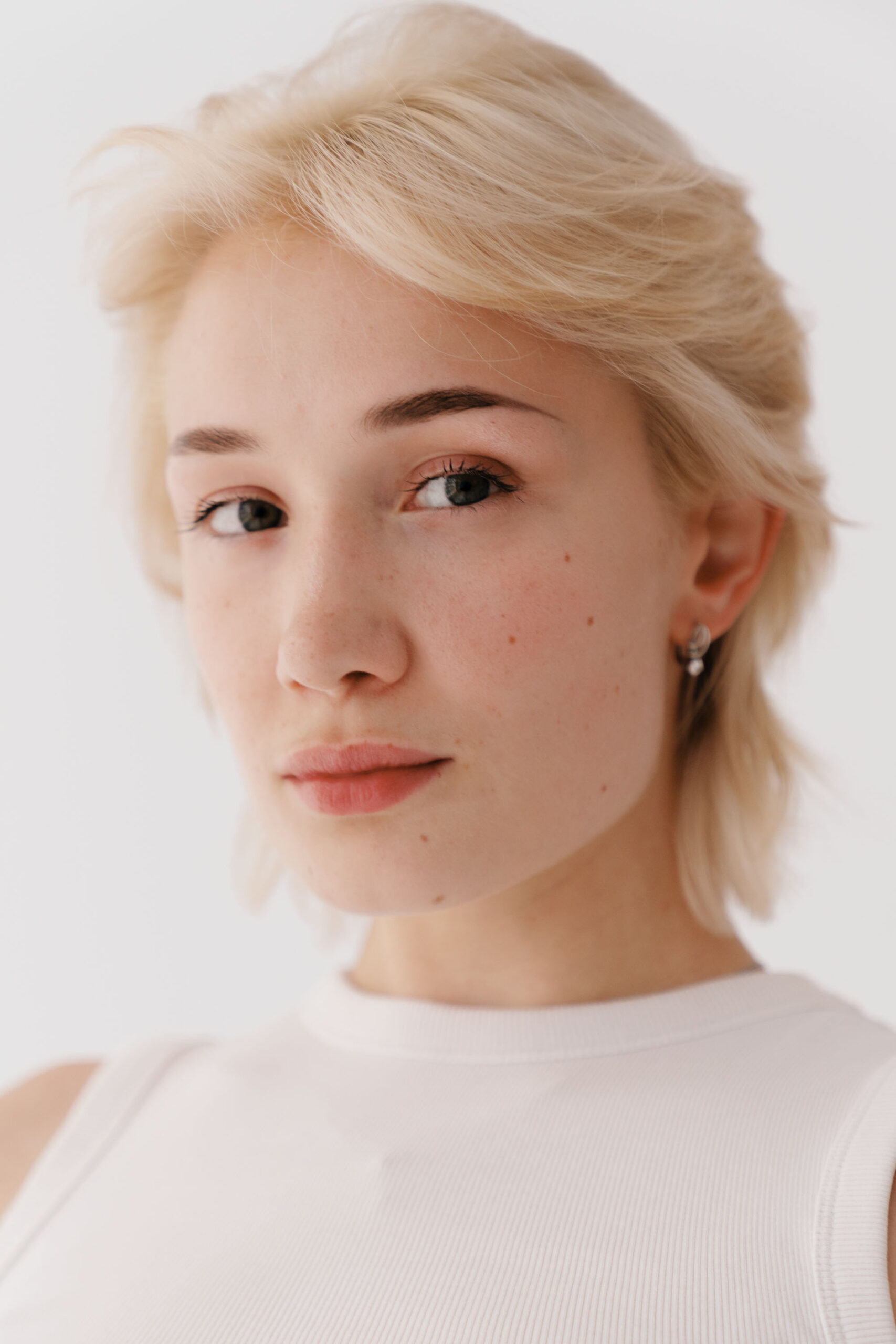 Person with short hair wearing a white top.