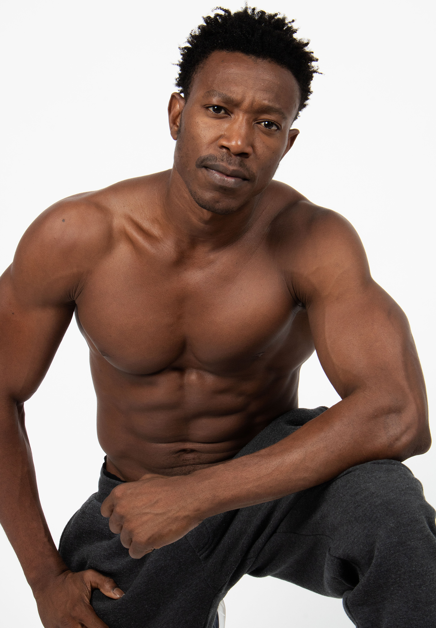 Fit man posing shirtless, muscular build.