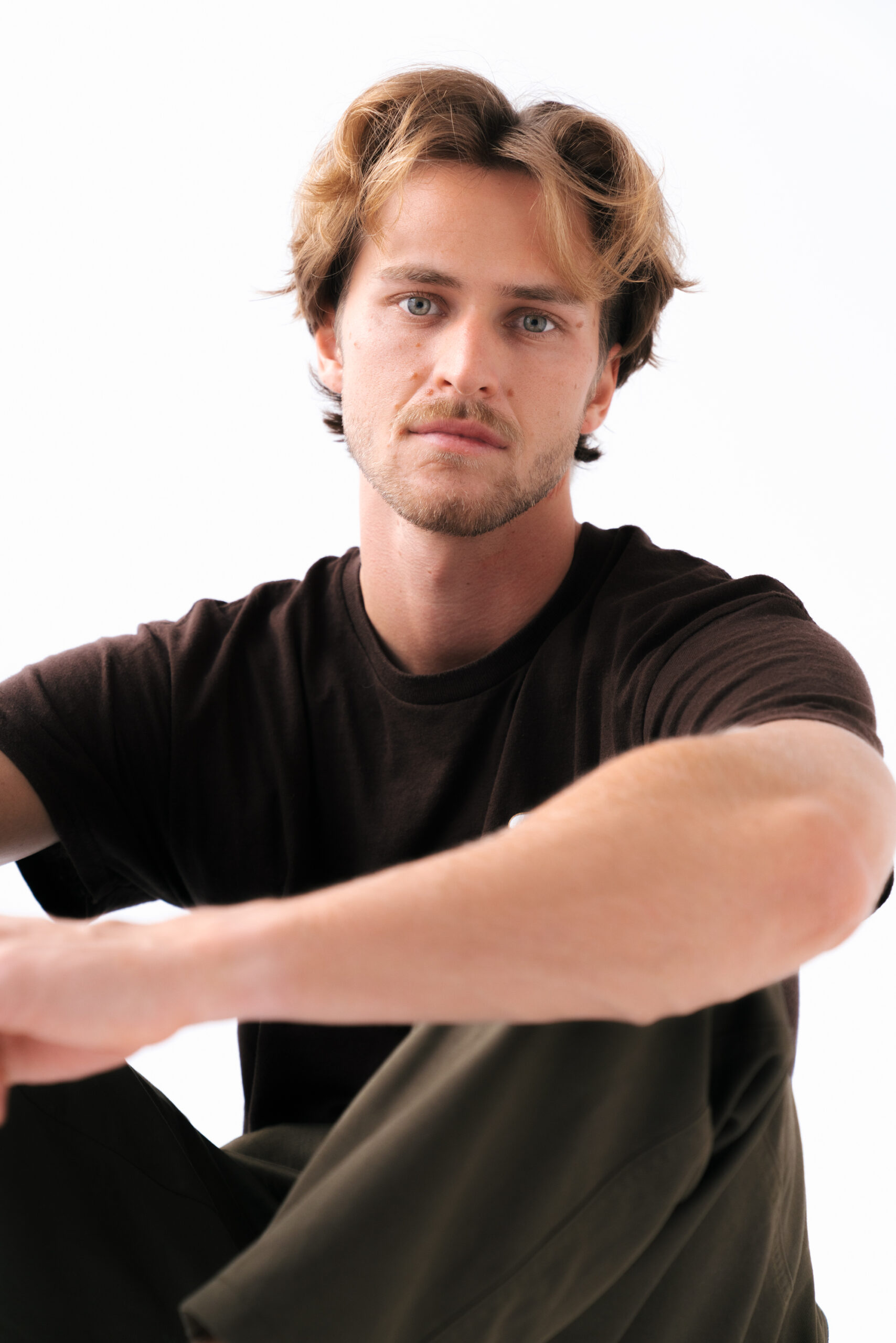 Person in brown shirt sitting, neutral expression.