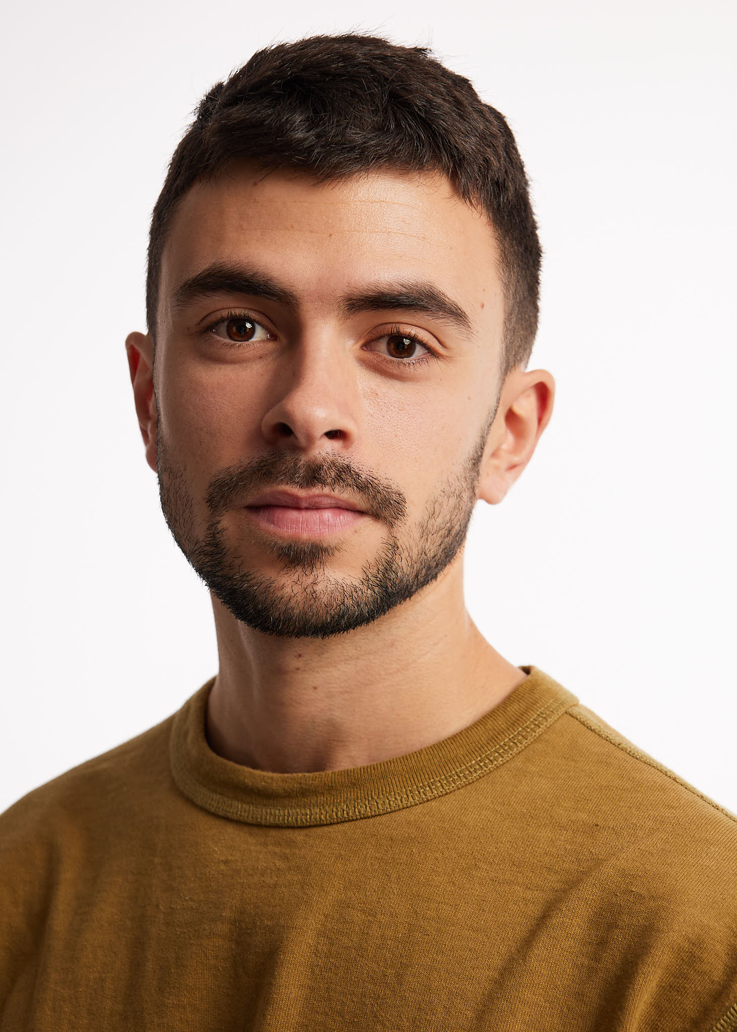 Man in brown shirt, neutral expression, white background.