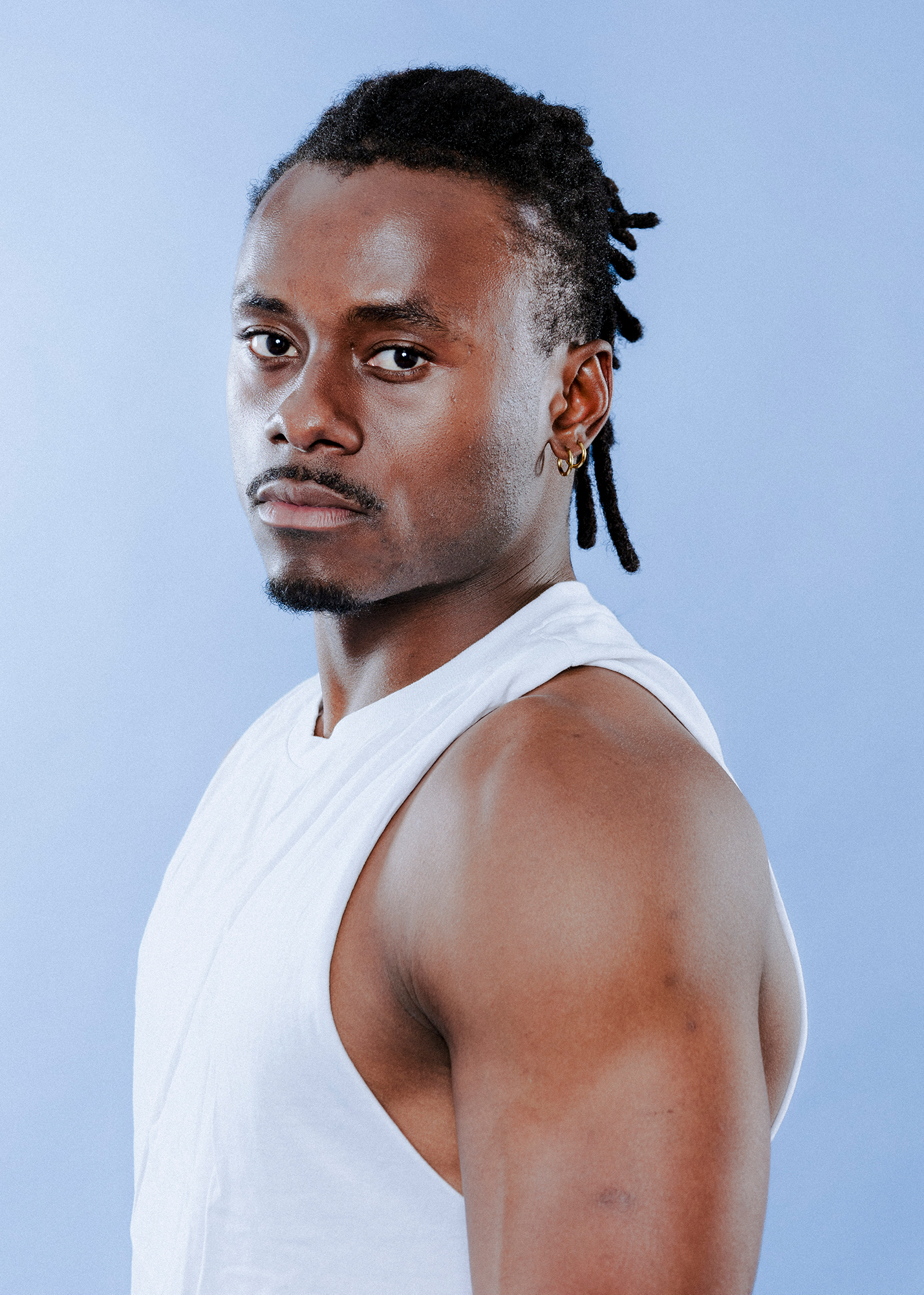 Man in white tank top looking serious.