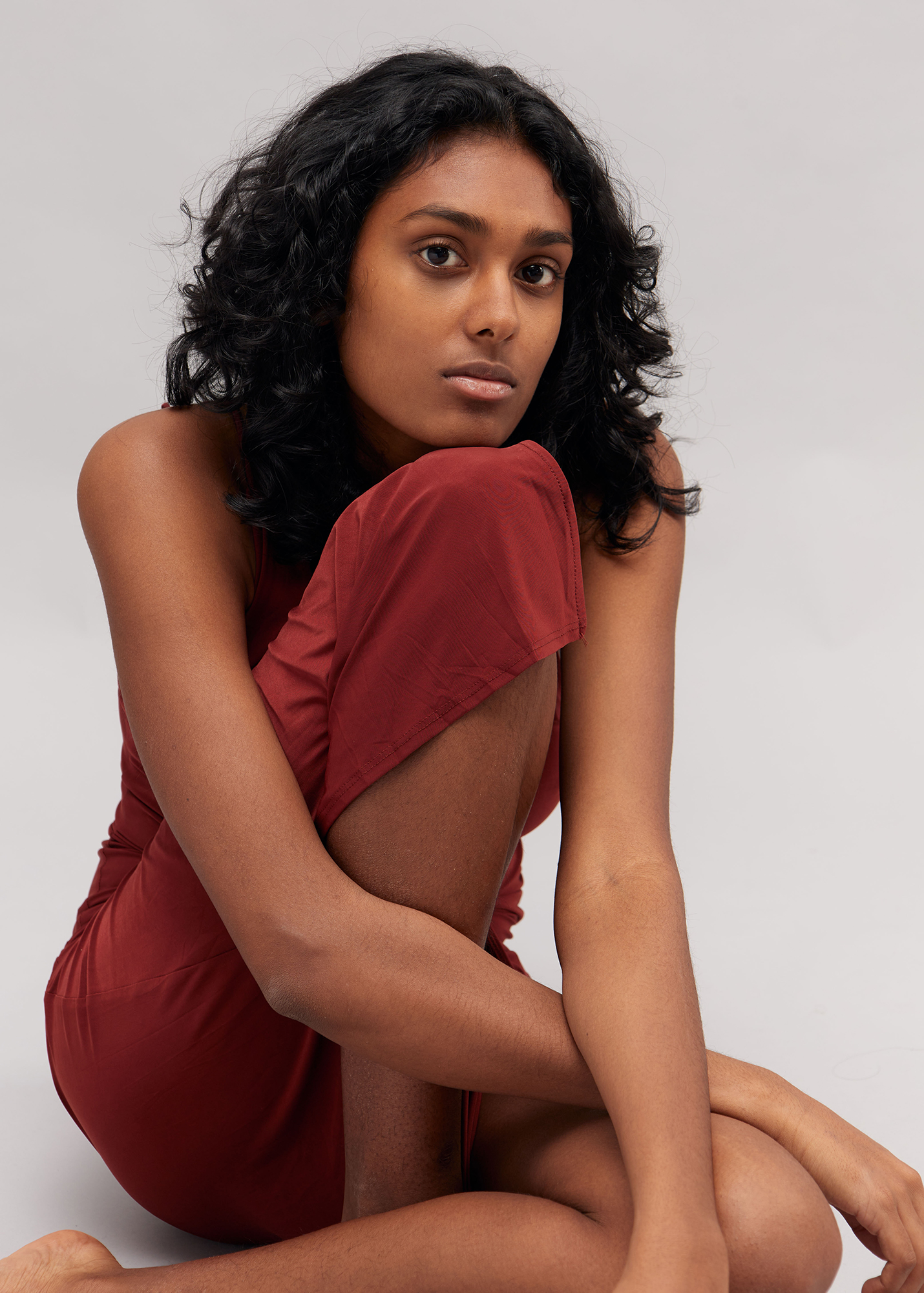 Person in red dress sitting thoughtfully.