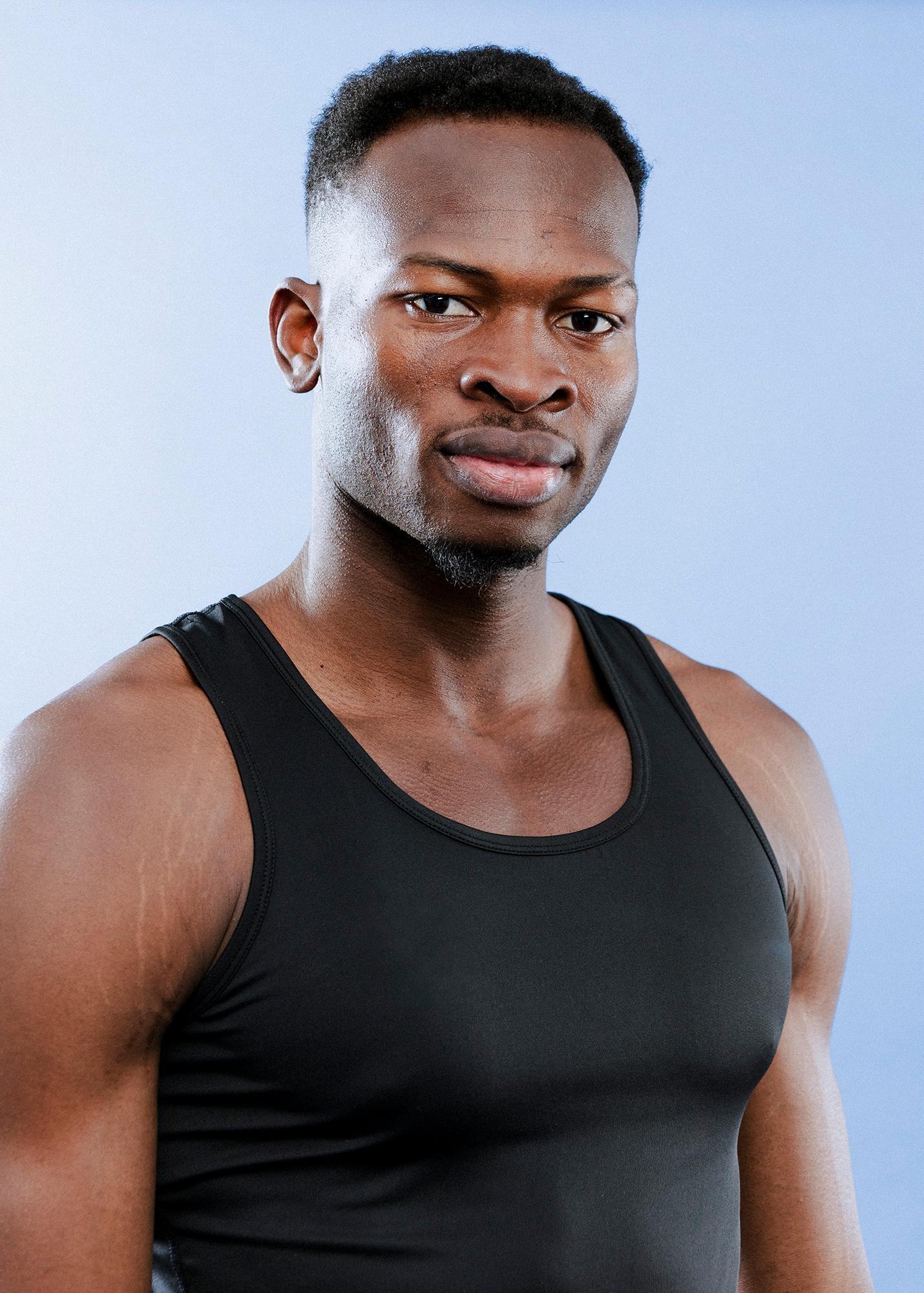 Man in black tank top, blue background.