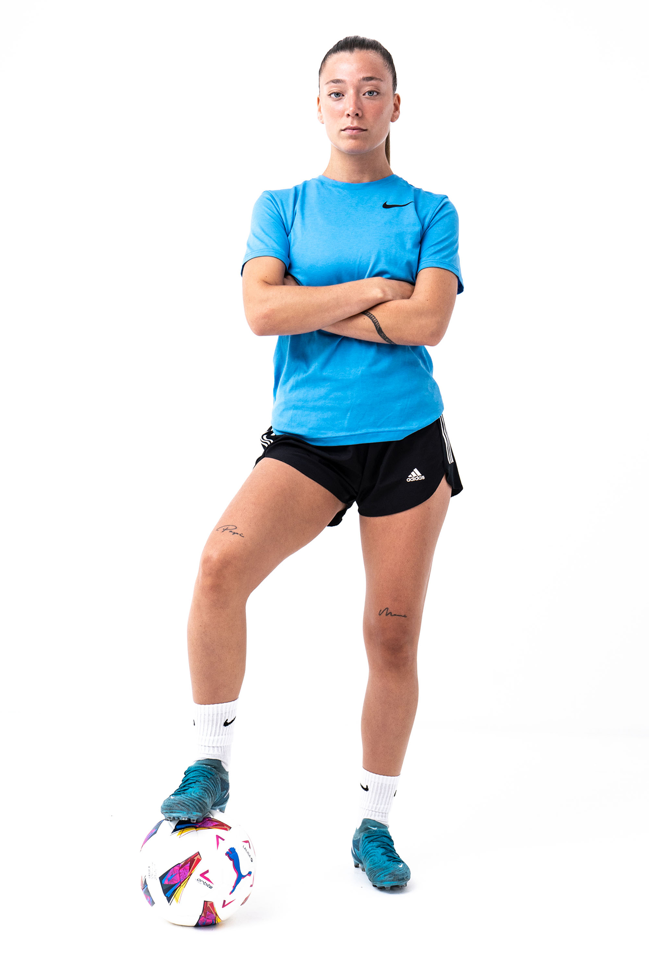Soccer player posing with ball, confident stance.