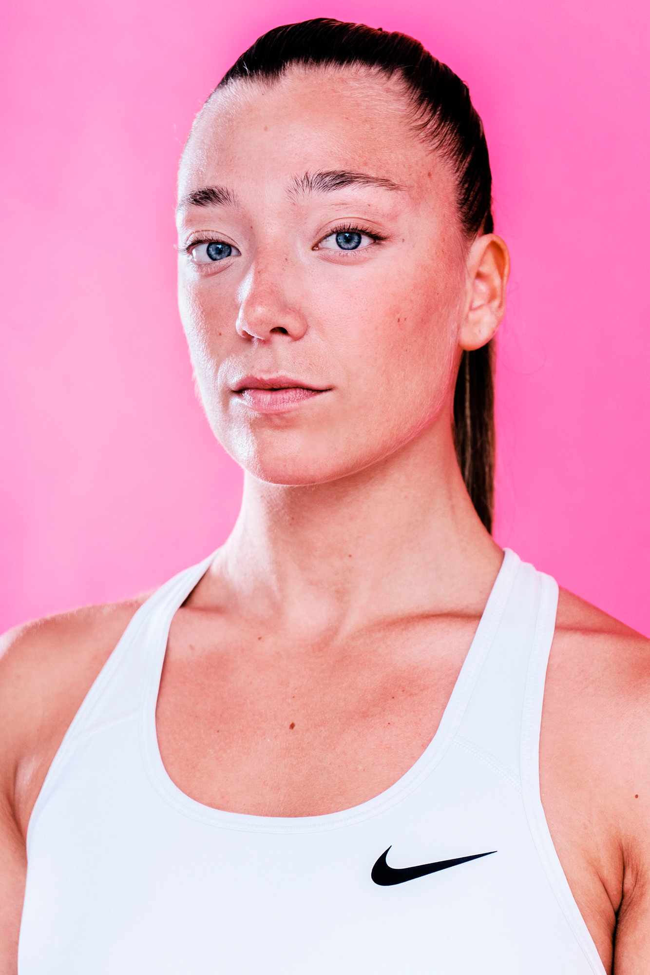 Athletic woman in white top on pink background.
