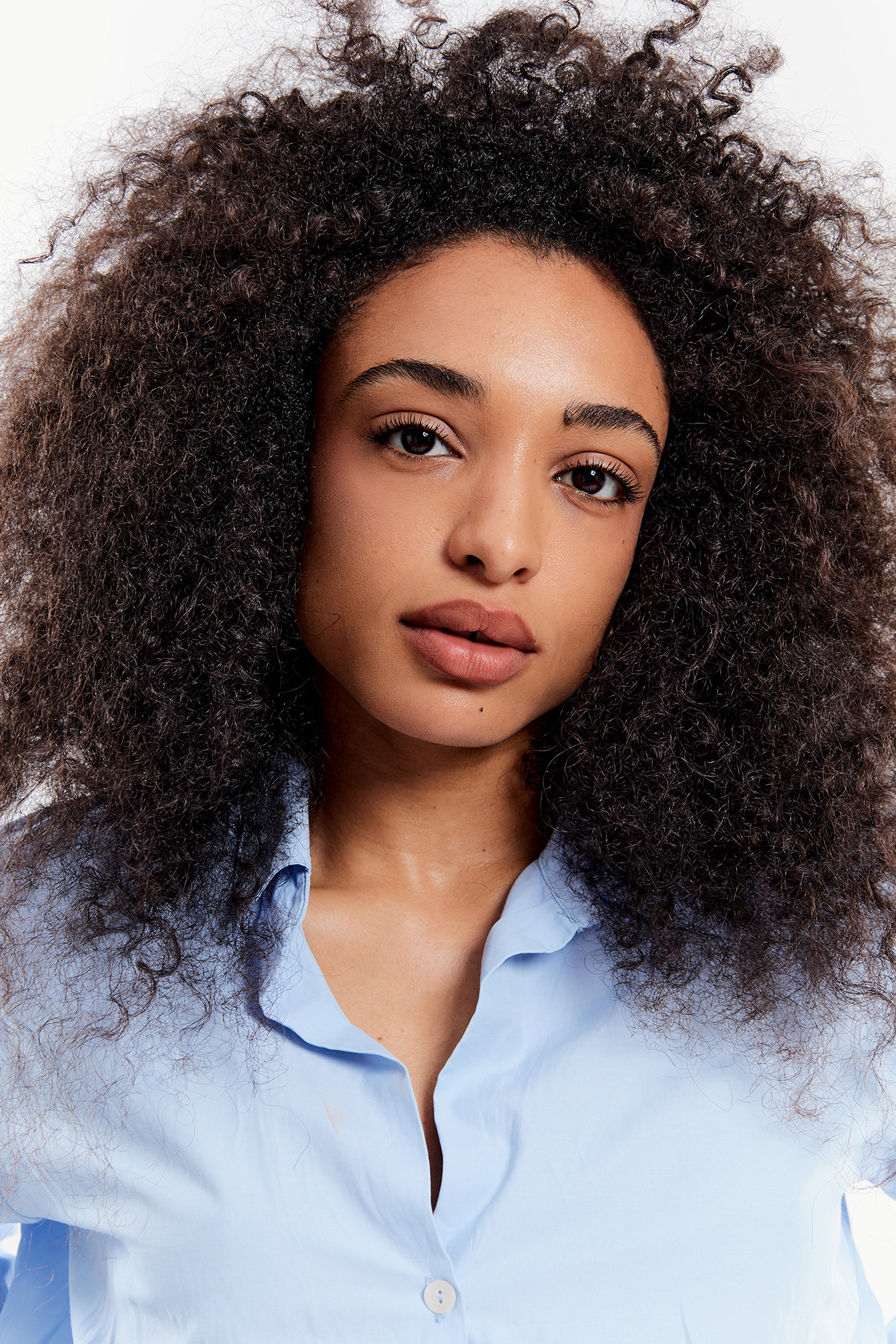 Woman with curly hair wearing blue shirt.