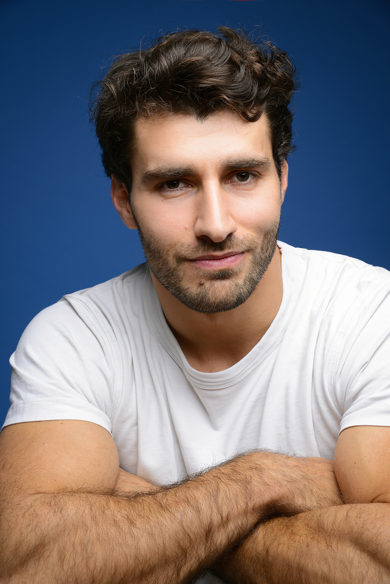 Smiling man in white shirt, blue background.