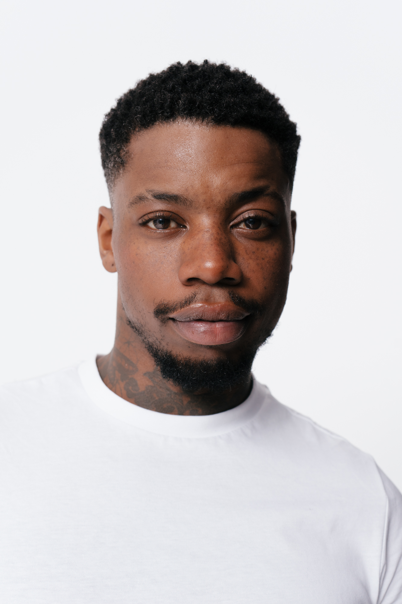 Man in white shirt with tattoos smiling