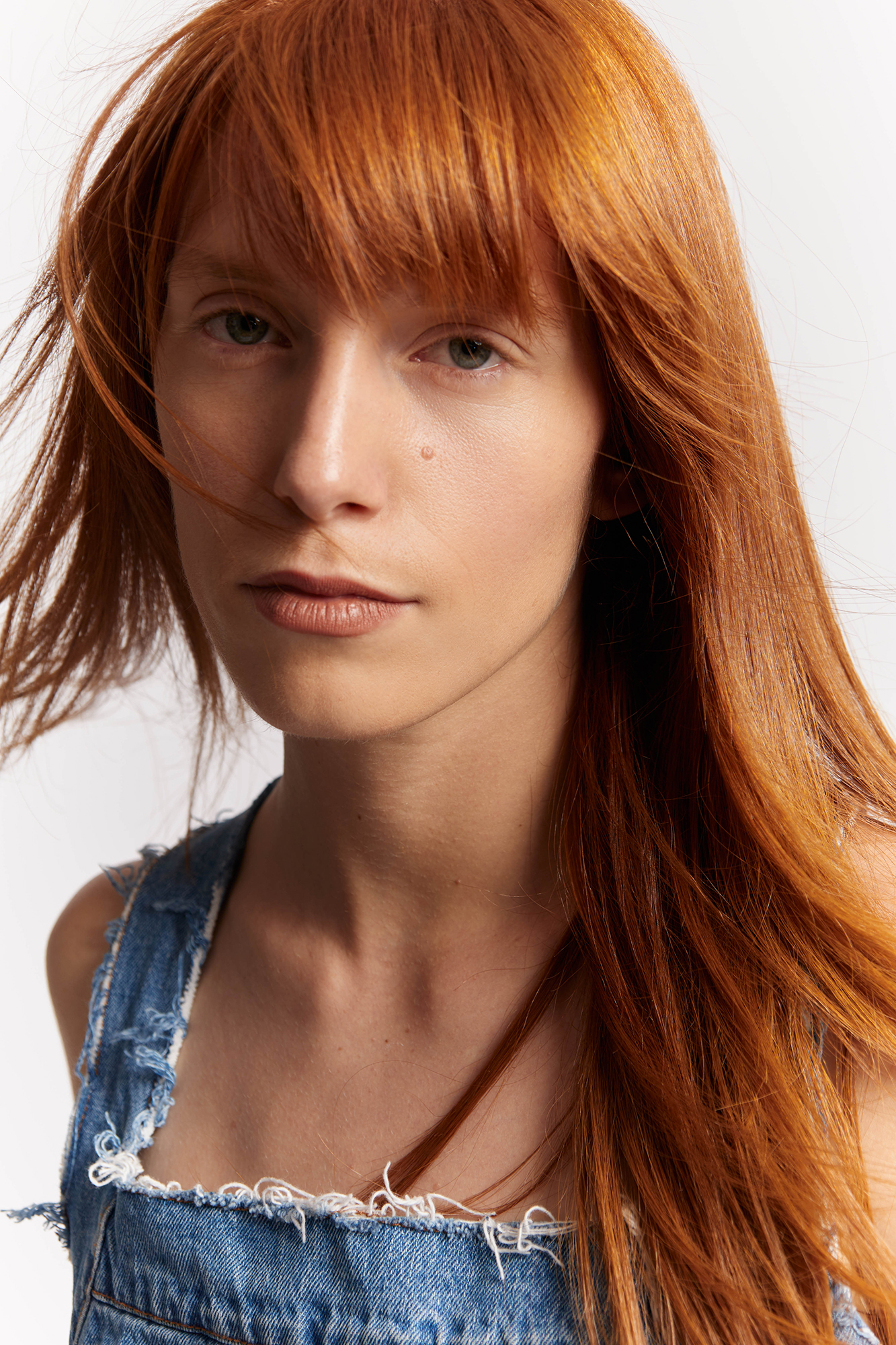 Person with long red hair wearing denim overalls.
