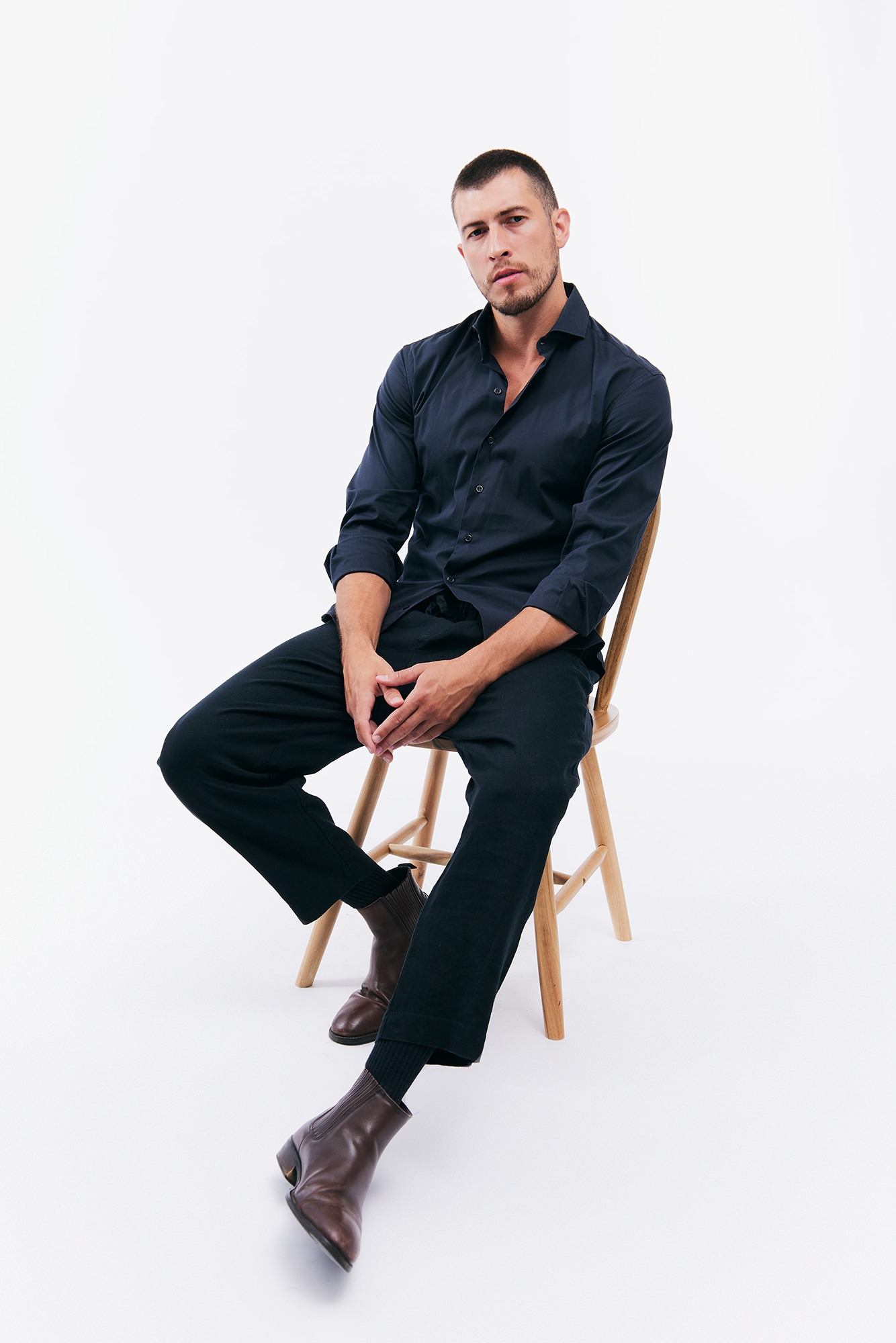 Man sitting on wooden chair in black outfit