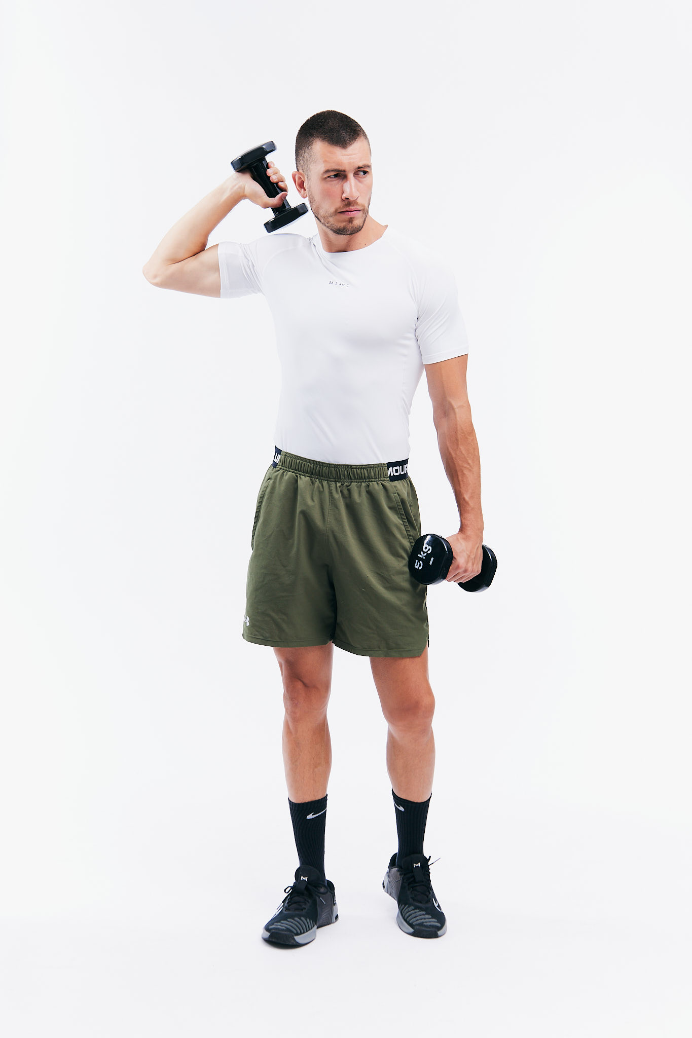 Man exercising with dumbbells in white shirt and shorts.