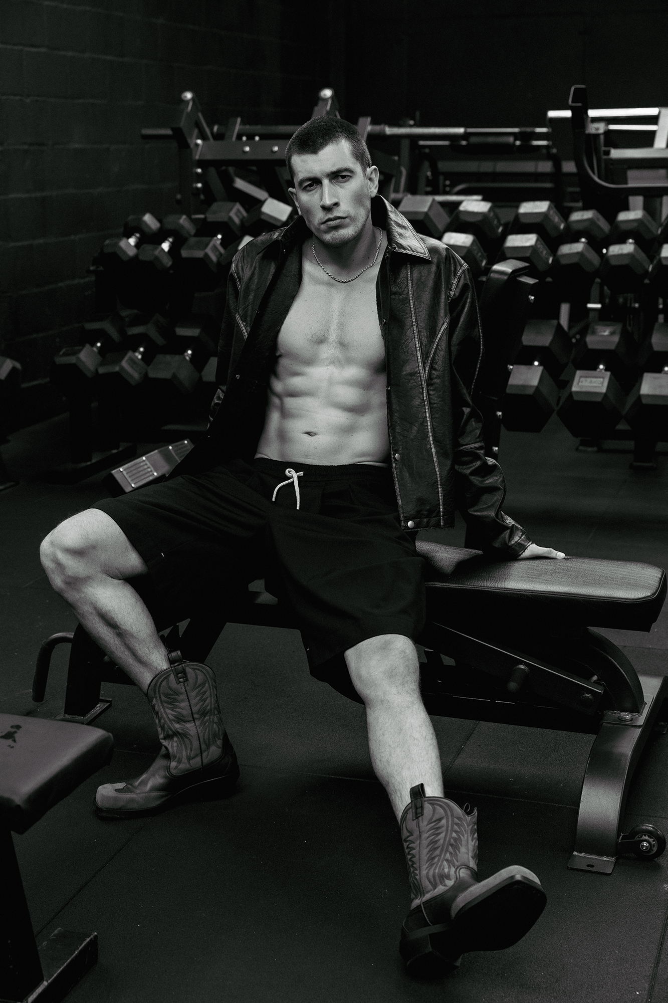 Man sitting on a gym bench, wearing cowboy boots.