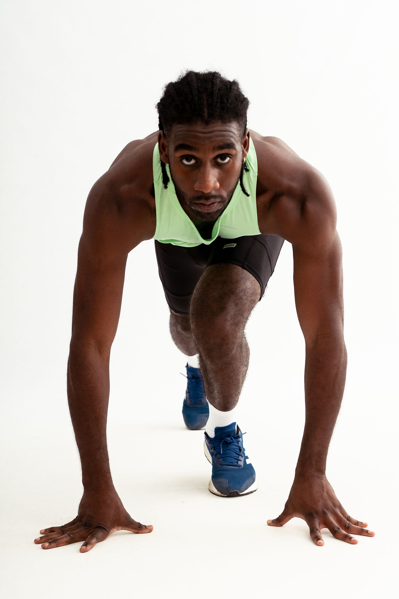 Athlete preparing to sprint in green tank top.