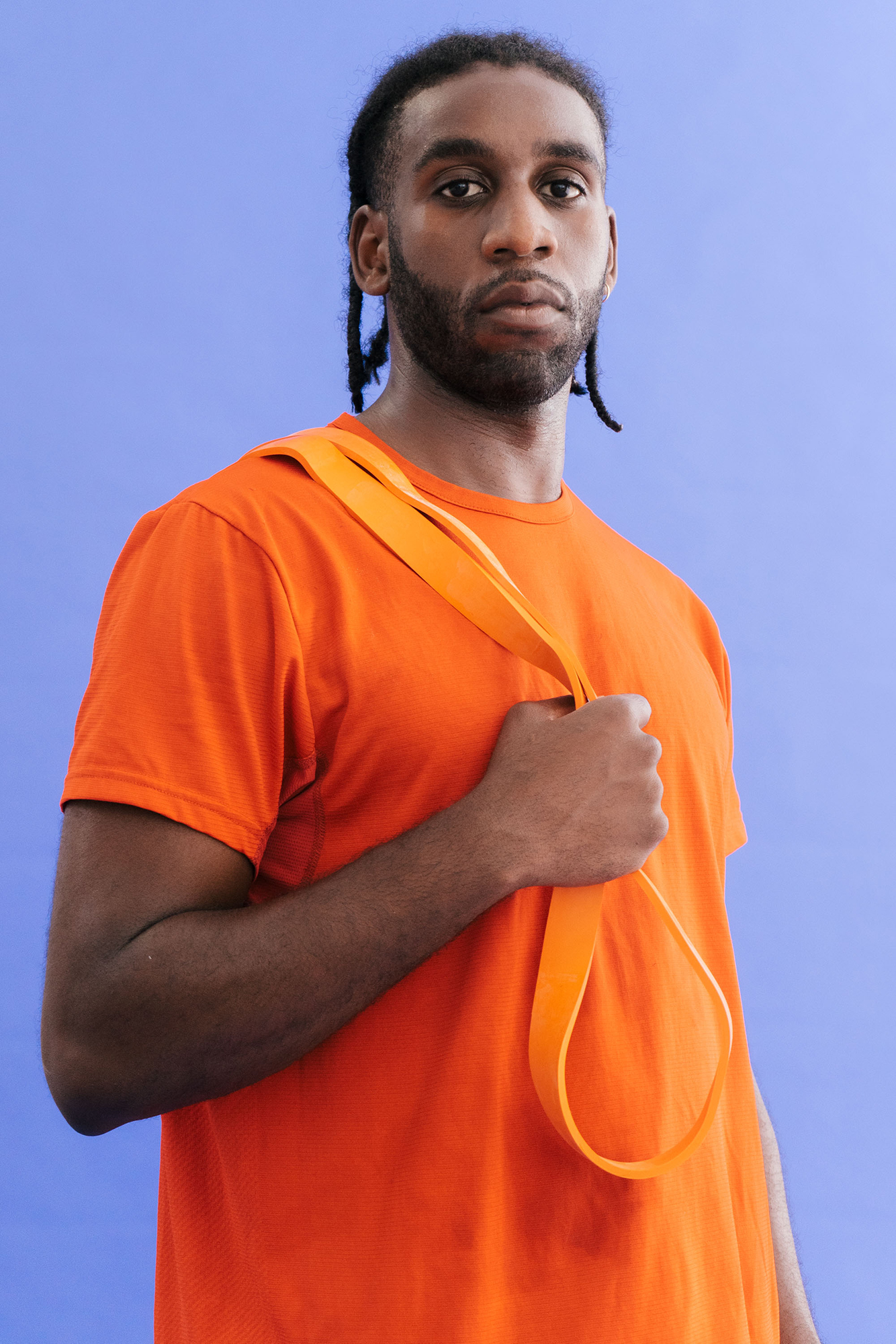 Person in orange shirt holding strap, blue background.