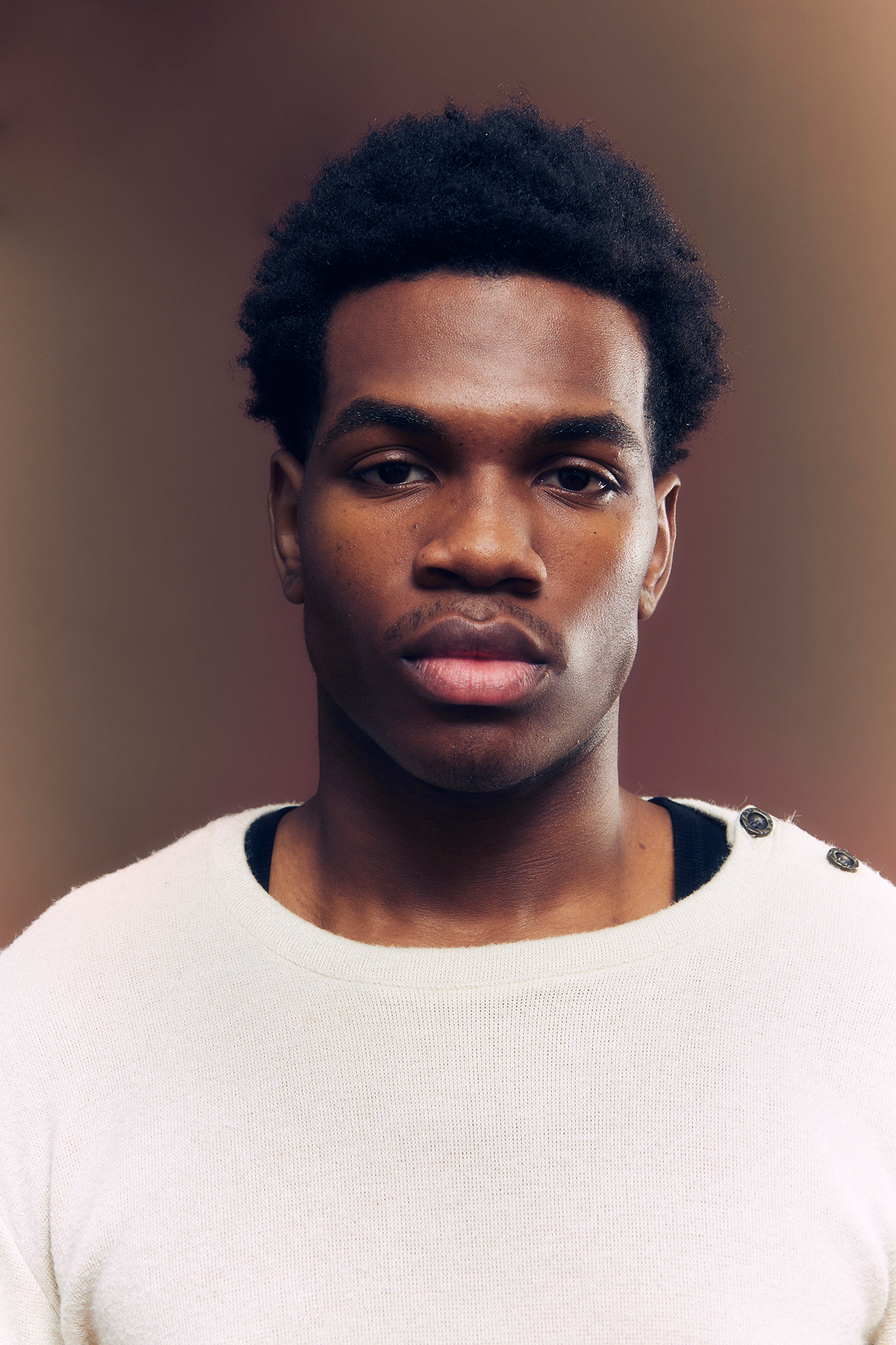 Person wearing a white sweater, neutral background.