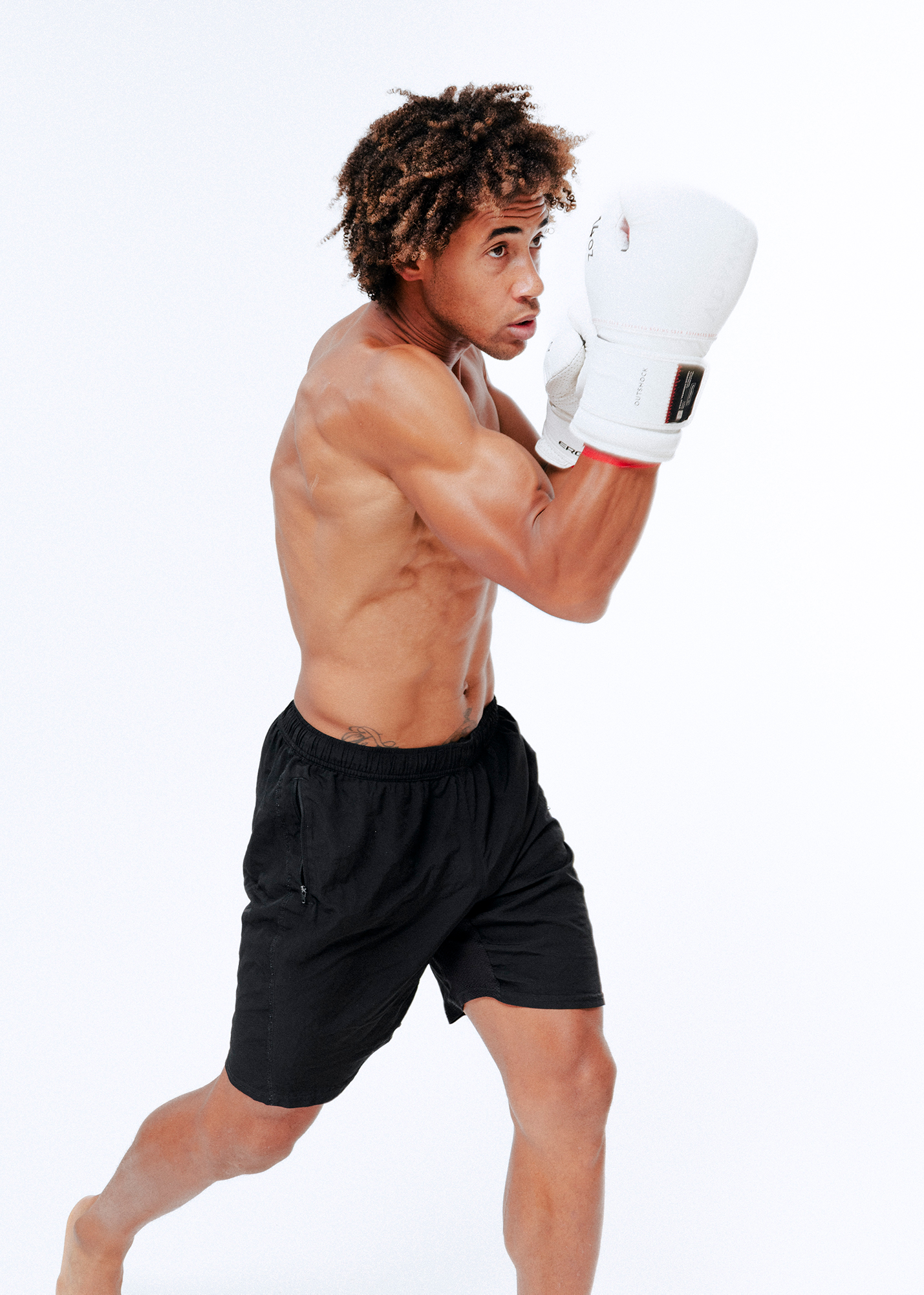 Man punching, wearing boxing gloves and shorts.