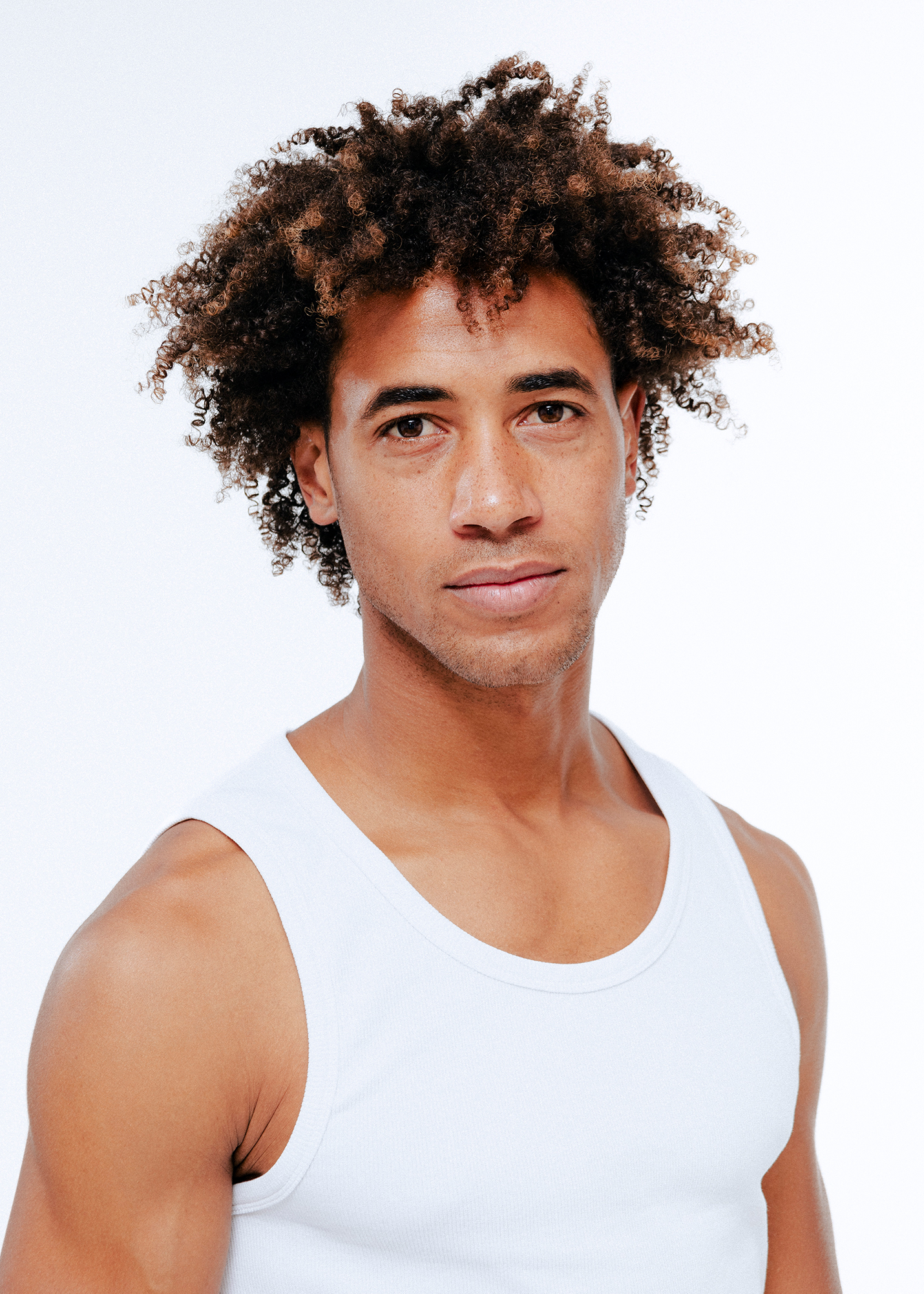 Man with curly hair in white tank top