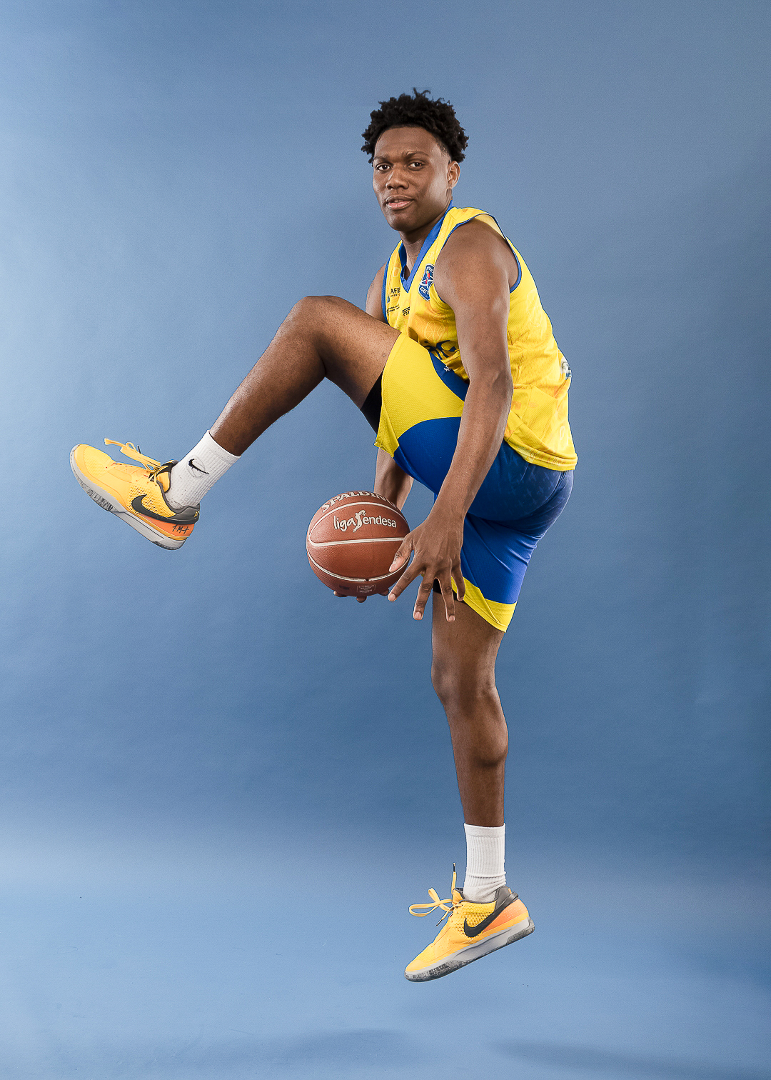 Basketball player posing with ball in studio.