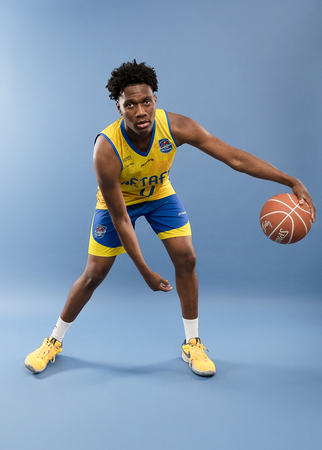 Basketball player dribbling in blue and yellow uniform.