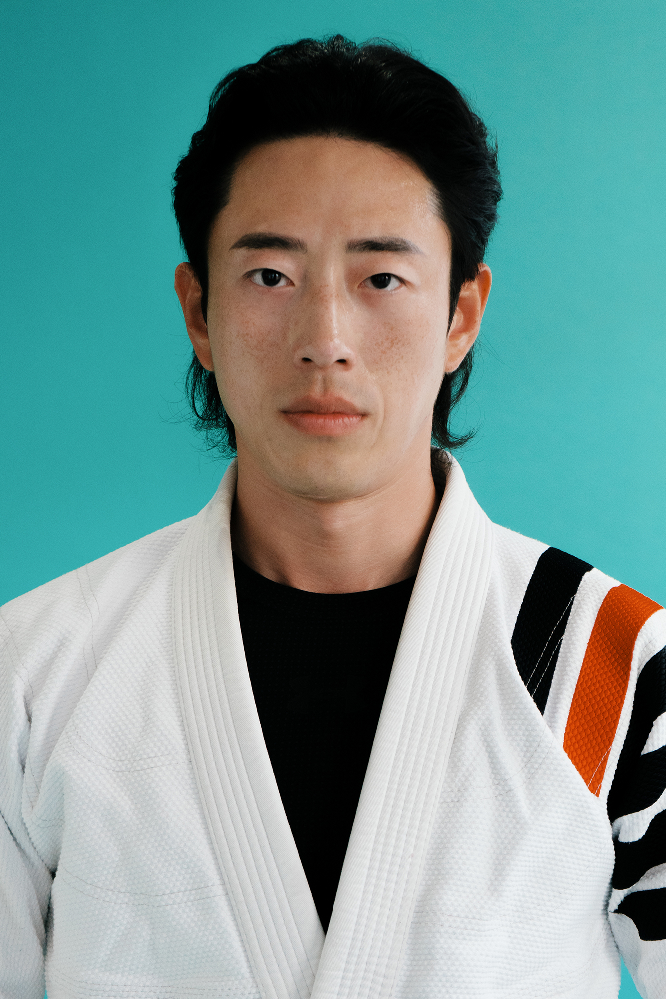 Man in judo uniform against teal background.