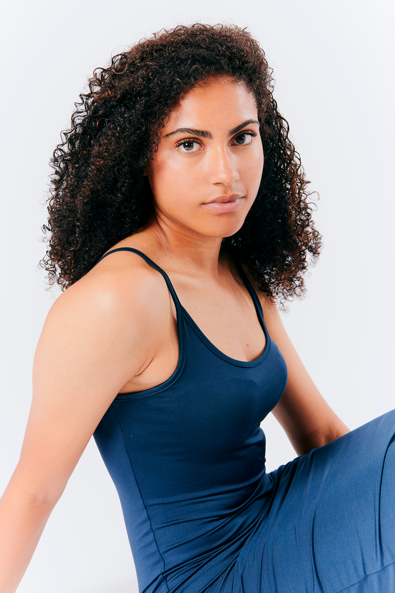 Woman in blue dress sitting in studio portrait.