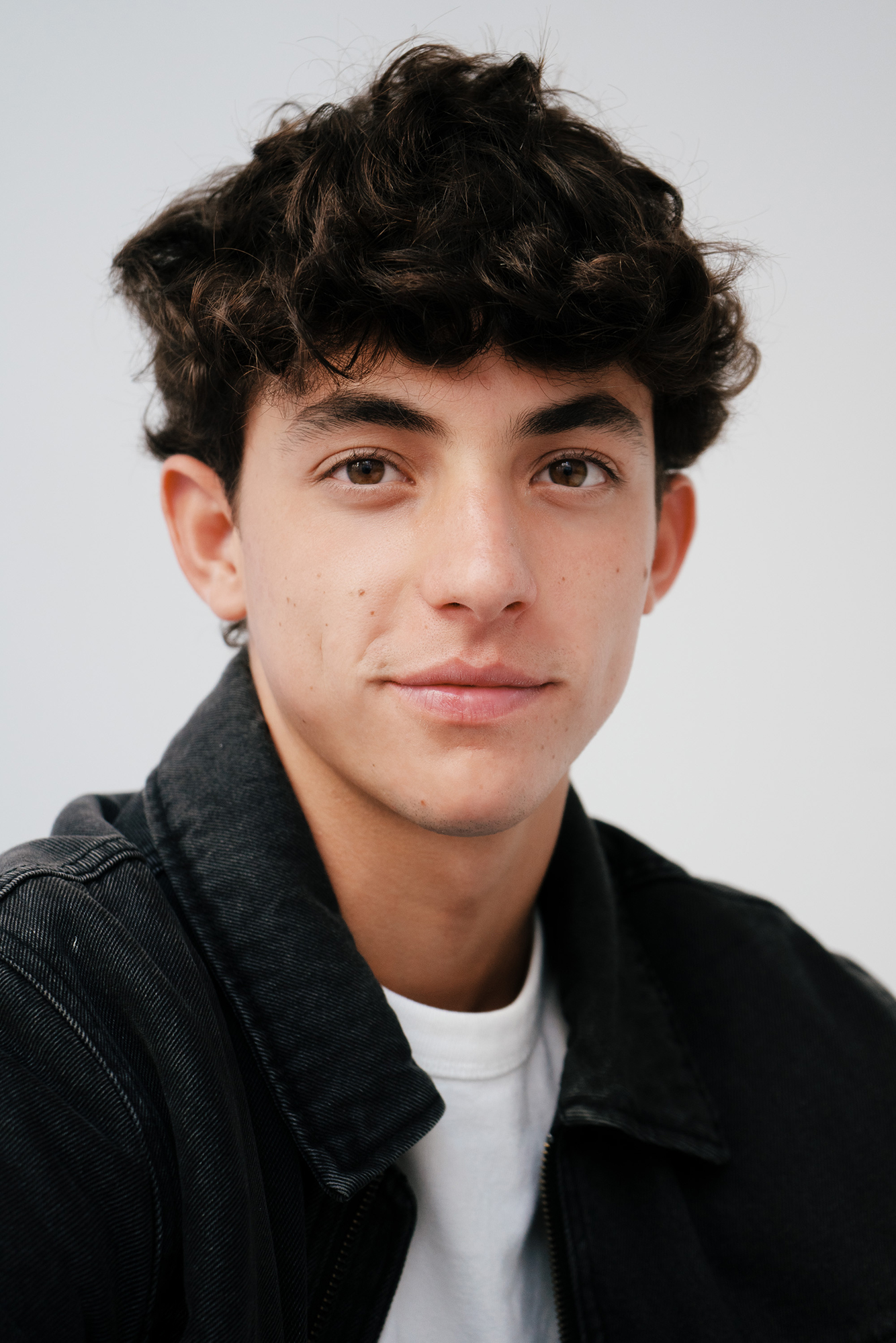 Young man in black jacket, neutral expression.