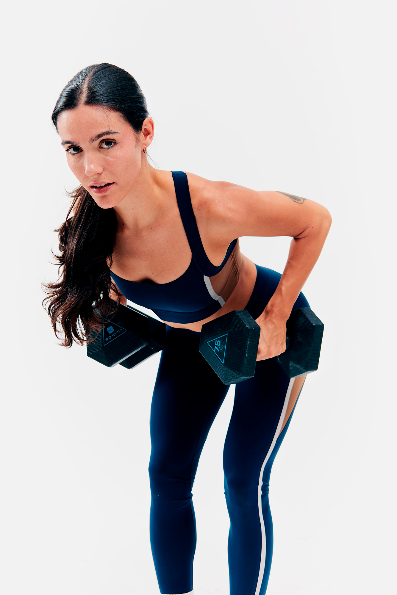 Woman exercising with dumbbells in workout attire.