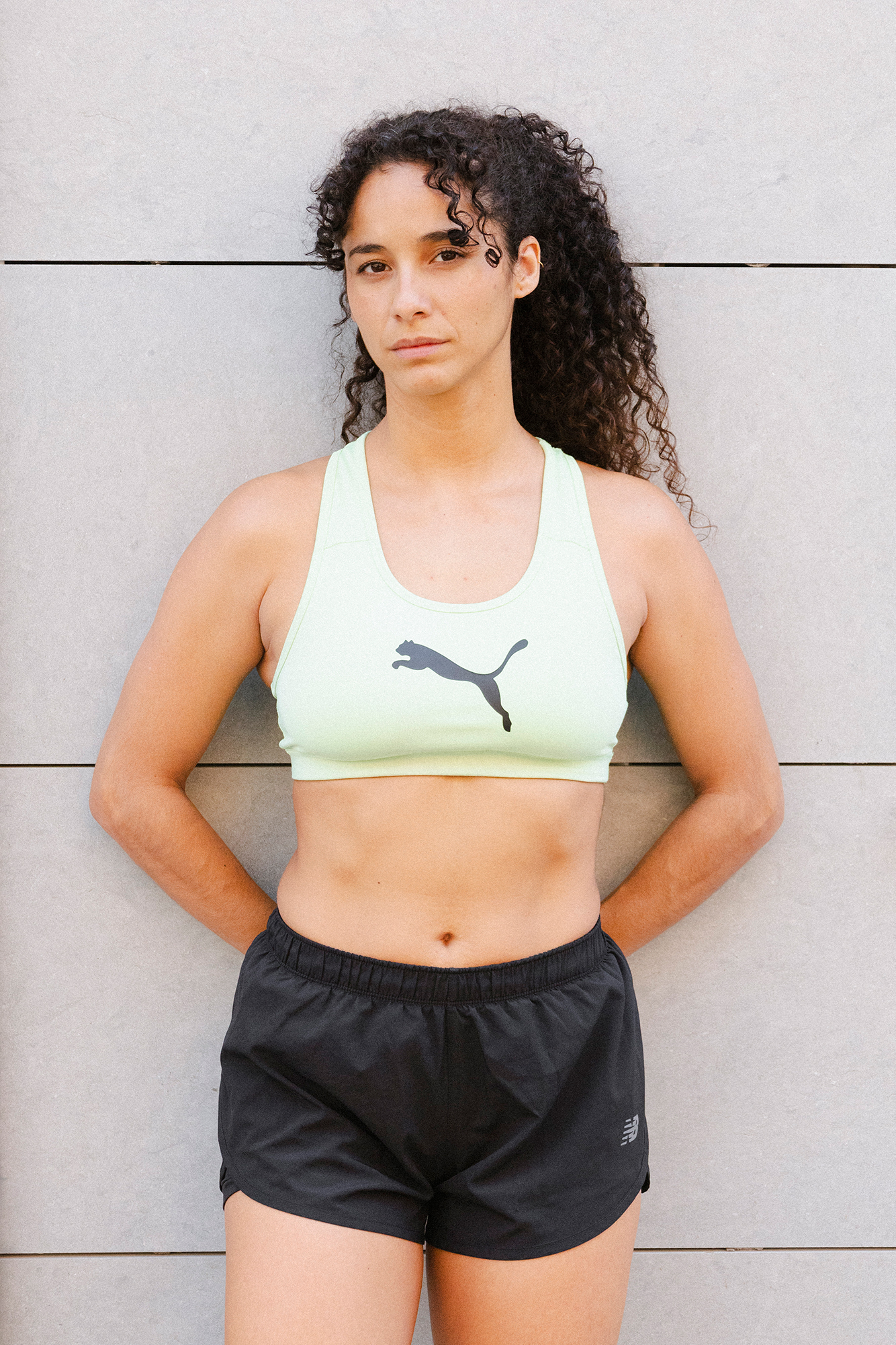 Woman in sportswear standing against a wall.