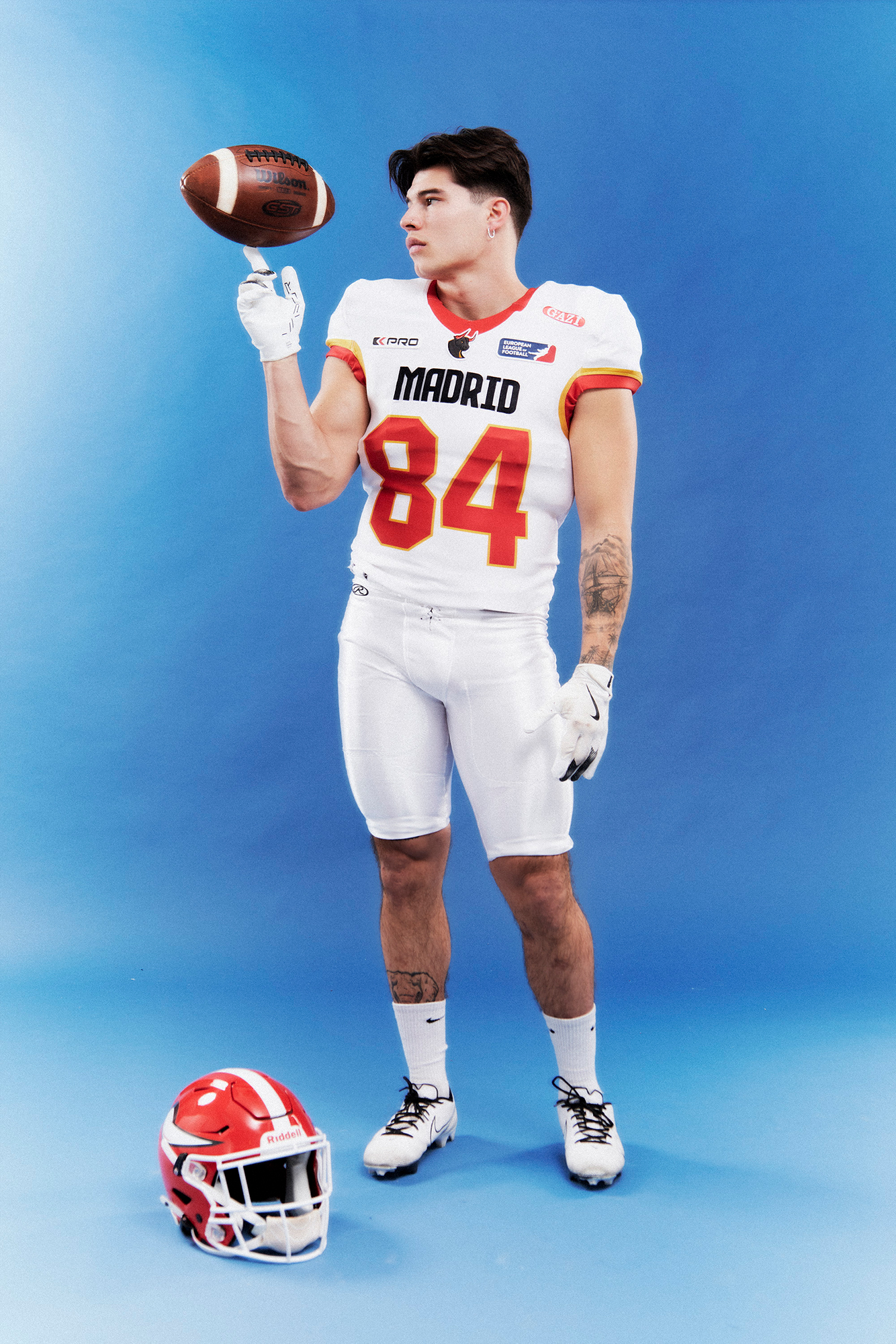 Football player balancing ball in uniform.