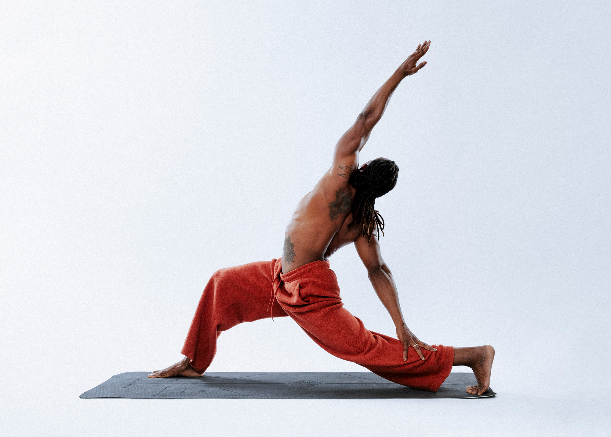 Person in yoga pose on mat, wearing red pants.