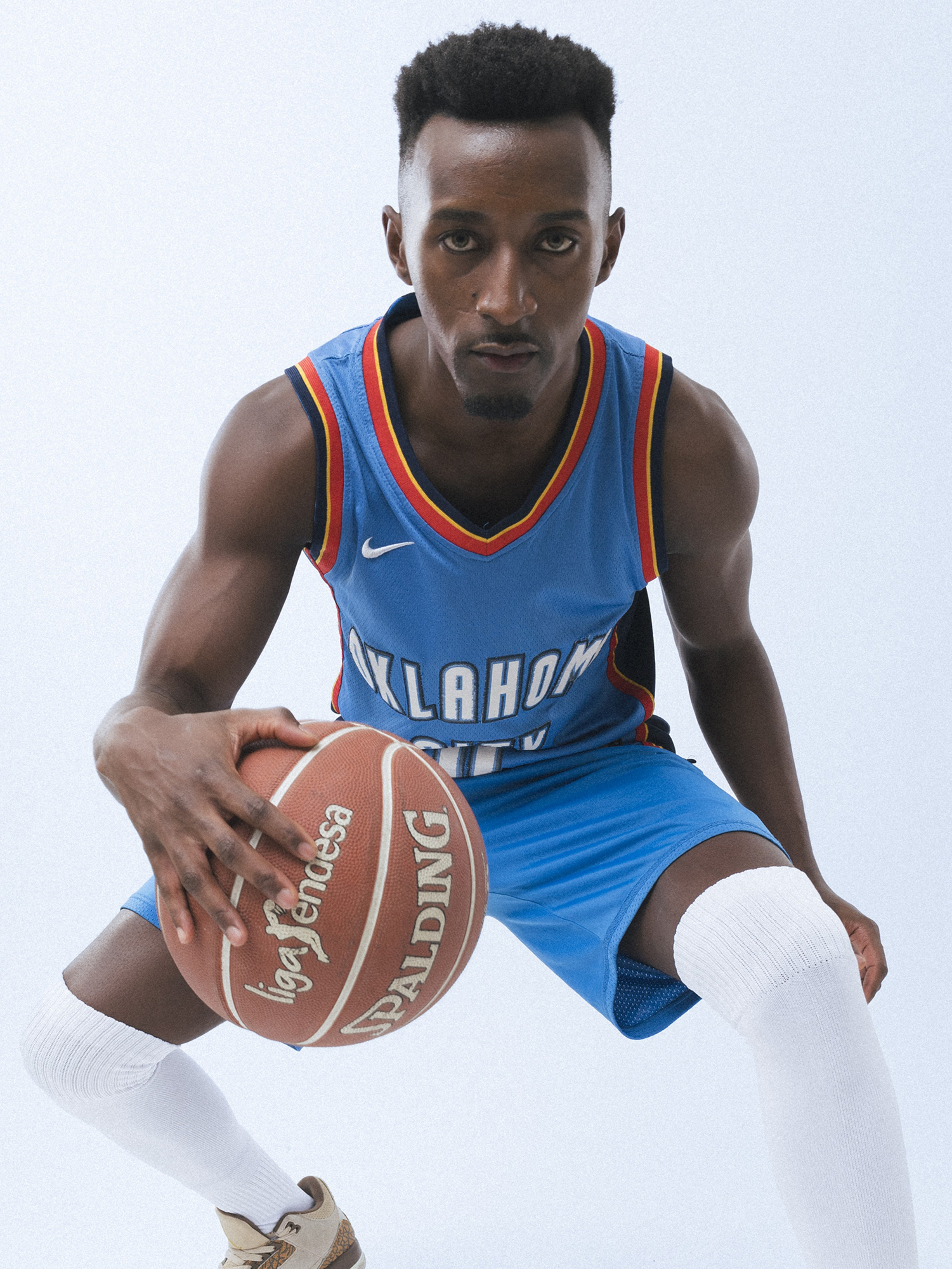 Basketball player dribbling ball in uniform.
