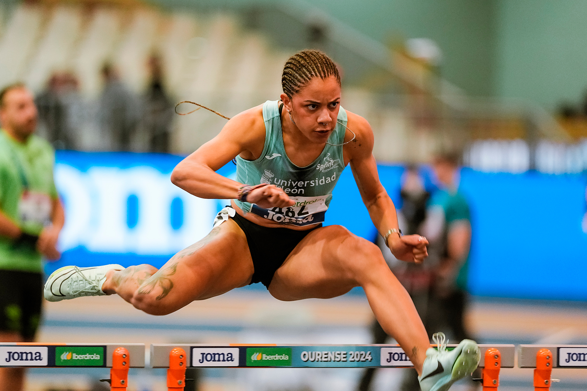 Athlete jumping over hurdle in competition.