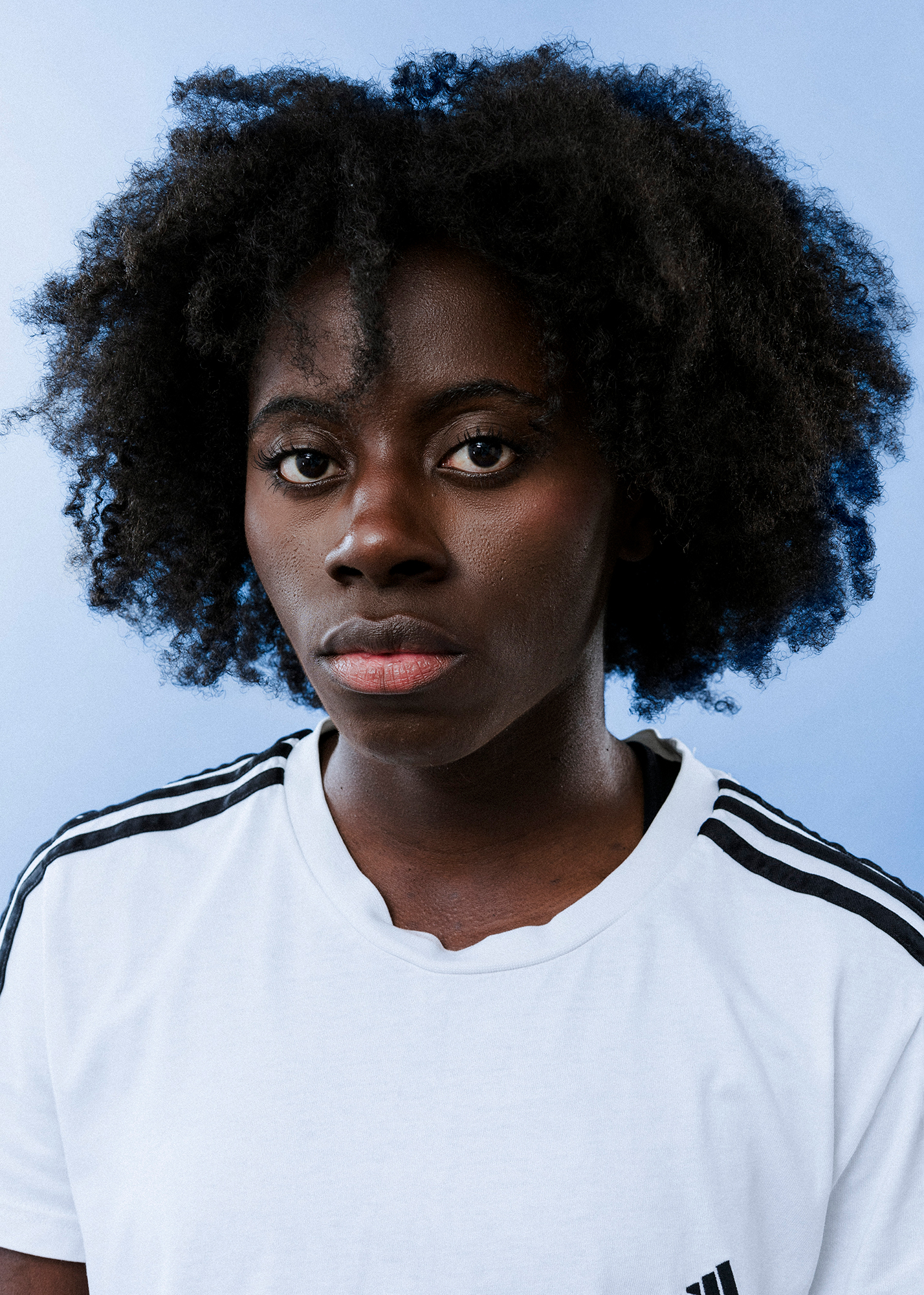 Person with curly hair wearing a striped white shirt.