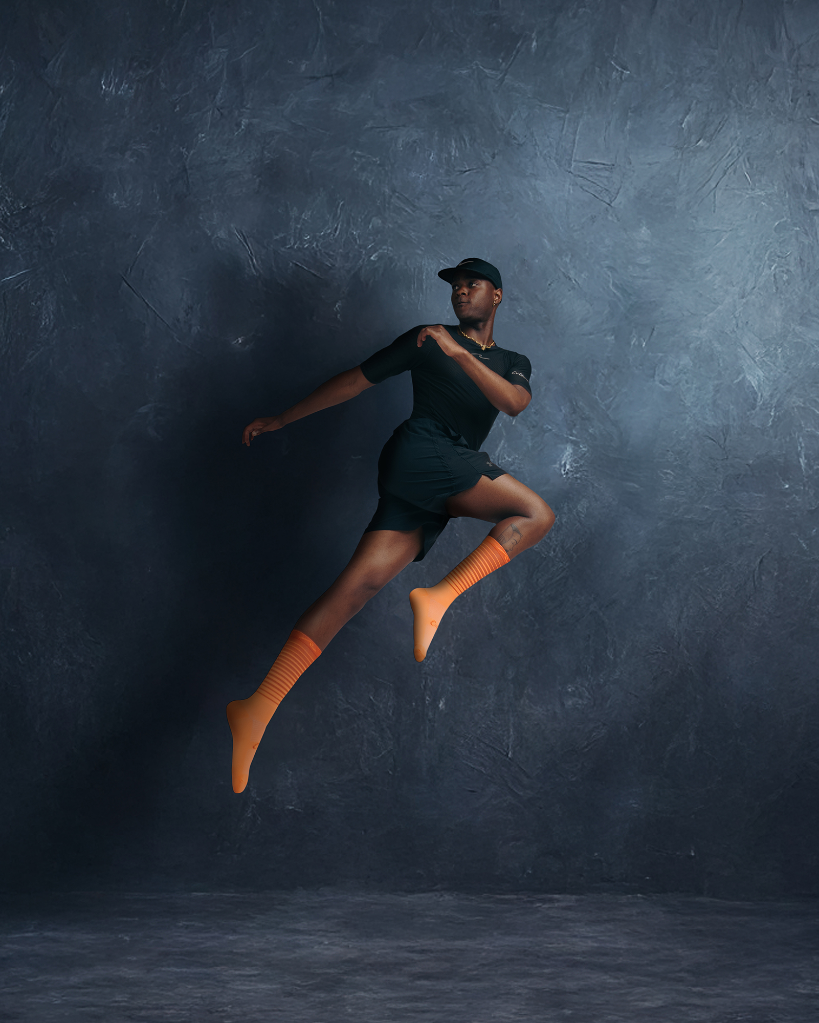 Person in mid-jump wearing orange socks and cap.